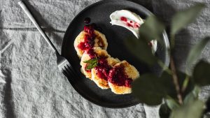 A tempting plate of pancakes topped with berry jam and sour cream, ideal for breakfast.
