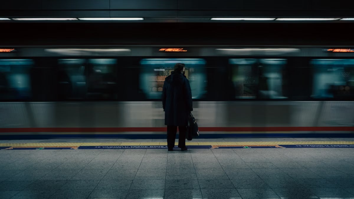 Silhouette of a solitary commuter on subway platform with train motion blur.